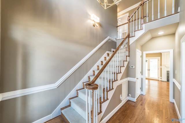 stairs featuring wood-type flooring and a towering ceiling