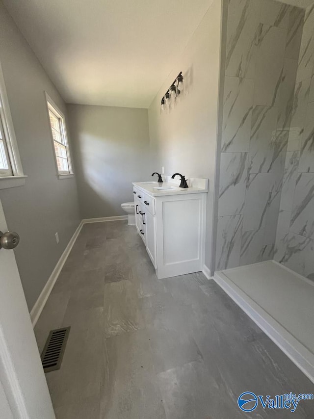 bathroom featuring vanity, toilet, and a tile shower