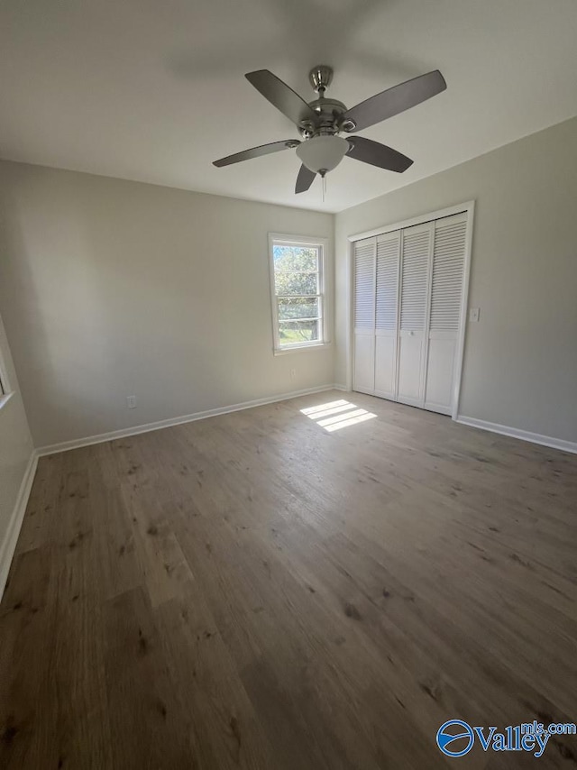 unfurnished bedroom with dark wood-type flooring, a closet, and ceiling fan