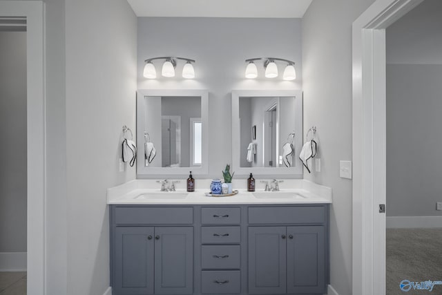 bathroom with double vanity, baseboards, walk in shower, and a sink