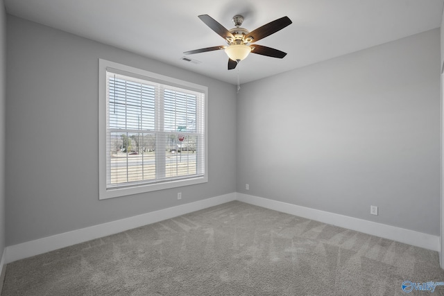 carpeted spare room featuring baseboards, visible vents, and ceiling fan