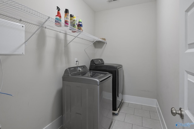 laundry area with visible vents, washer and clothes dryer, light tile patterned flooring, baseboards, and laundry area