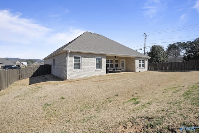 rear view of house featuring a patio, a fenced backyard, roof with shingles, brick siding, and ceiling fan