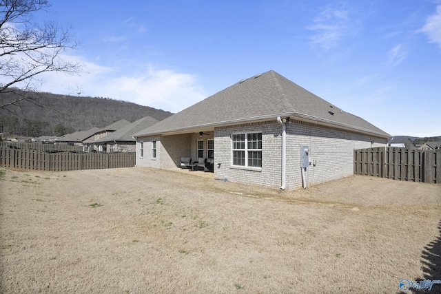 back of property featuring brick siding, a ceiling fan, and fence