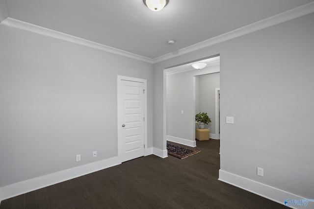 spare room featuring ornamental molding, baseboards, and wood finished floors