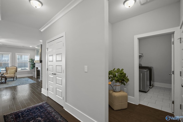 entrance foyer with a fireplace, wood finished floors, crown molding, and separate washer and dryer