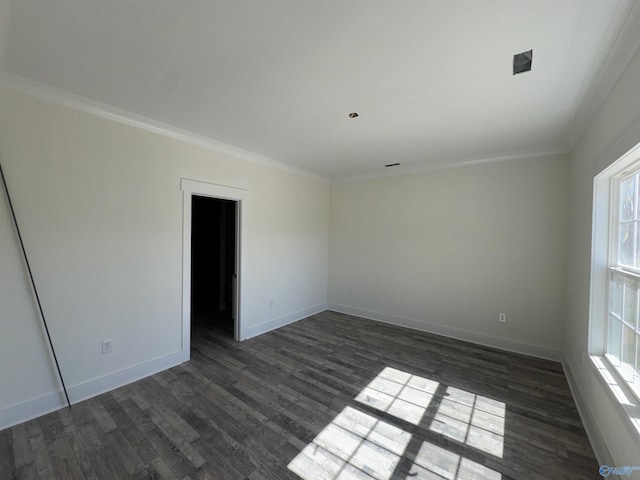 empty room with dark wood-style floors, crown molding, and baseboards