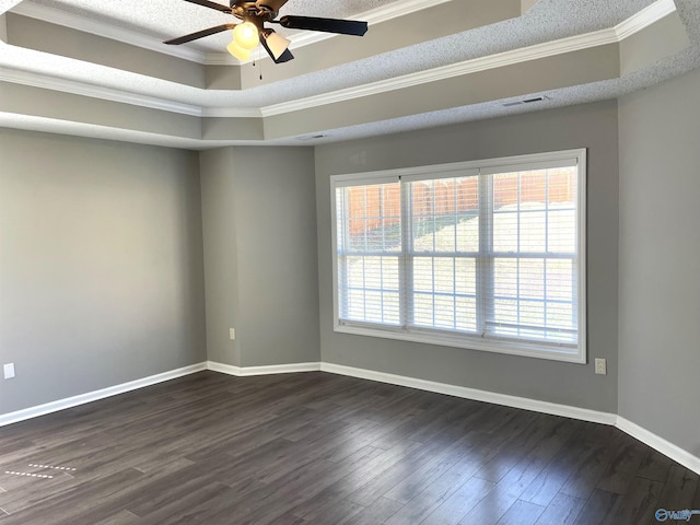 unfurnished room with dark wood finished floors, a raised ceiling, visible vents, ornamental molding, and baseboards