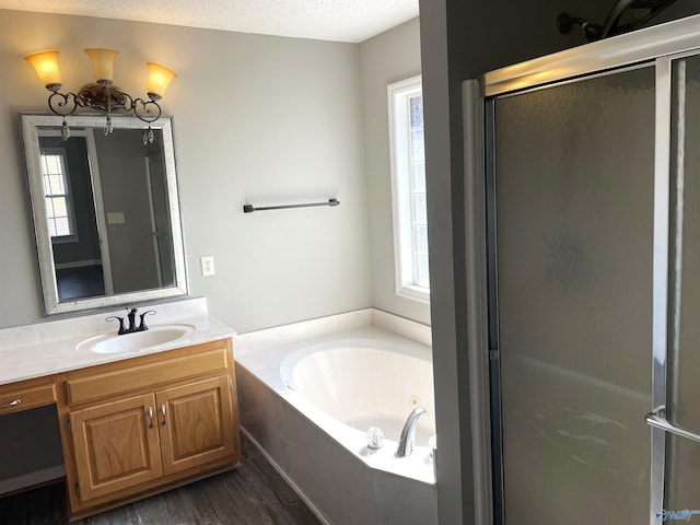 bathroom with a garden tub, a stall shower, a textured ceiling, vanity, and wood finished floors