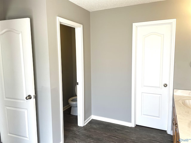 bathroom featuring toilet, vanity, a textured ceiling, wood finished floors, and baseboards