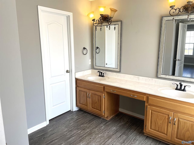 bathroom featuring double vanity, a sink, baseboards, and wood finished floors