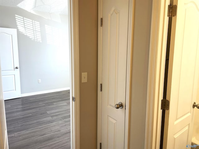 hall with dark wood-style flooring and baseboards