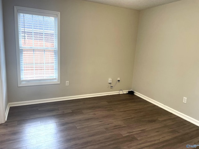 empty room featuring dark wood-style floors, a textured ceiling, and baseboards