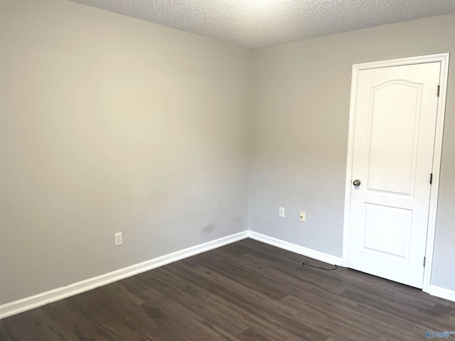 unfurnished room featuring a textured ceiling, dark wood-style flooring, and baseboards