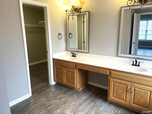 bathroom with wood finished floors, a sink, an inviting chandelier, and double vanity