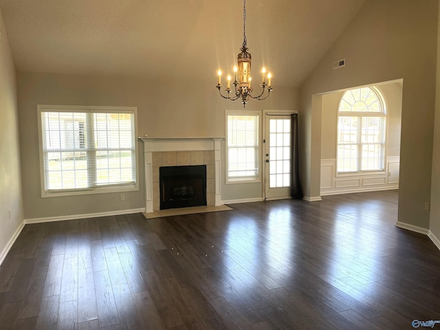 unfurnished living room featuring a chandelier, high vaulted ceiling, visible vents, a tiled fireplace, and dark wood finished floors