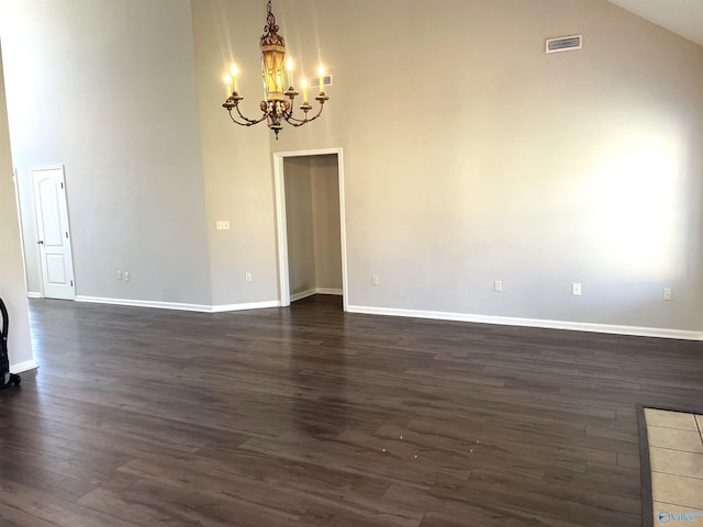 unfurnished room with visible vents, dark wood finished floors, baseboards, an inviting chandelier, and high vaulted ceiling