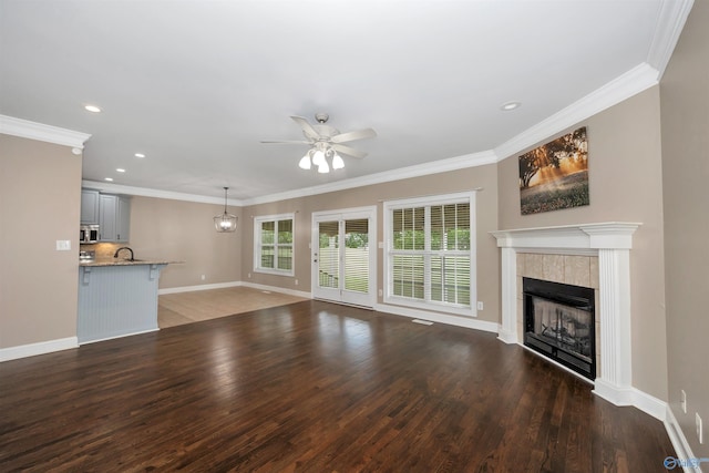 22656 Riviera Dr, Athens, AL 35613 - unfurnished living room with a ceiling fan, a tiled fireplace, baseboards, wood finished floors, and crown molding