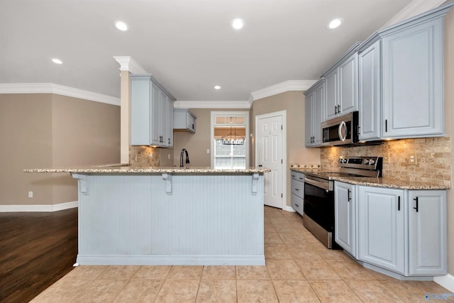 22656 Riviera Dr, Athens, AL 35613 - kitchen with stainless steel appliances, a peninsula, a kitchen breakfast bar, light stone counters, and baseboards