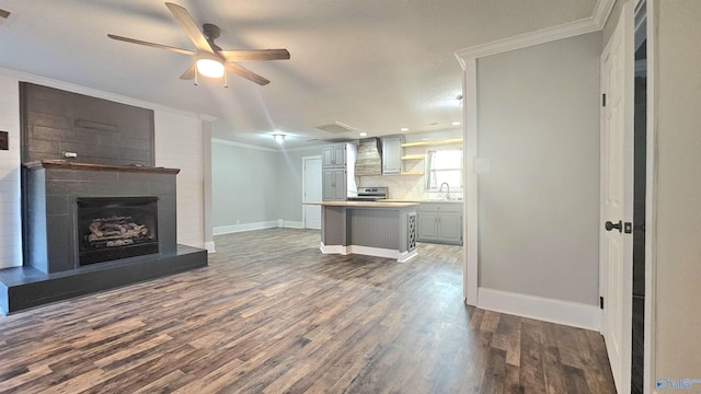 unfurnished living room featuring sink, wood-type flooring, ceiling fan, and crown molding