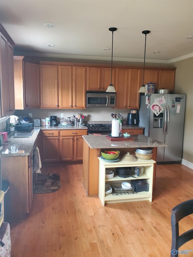 kitchen featuring a center island, sink, stainless steel appliances, light hardwood / wood-style flooring, and pendant lighting