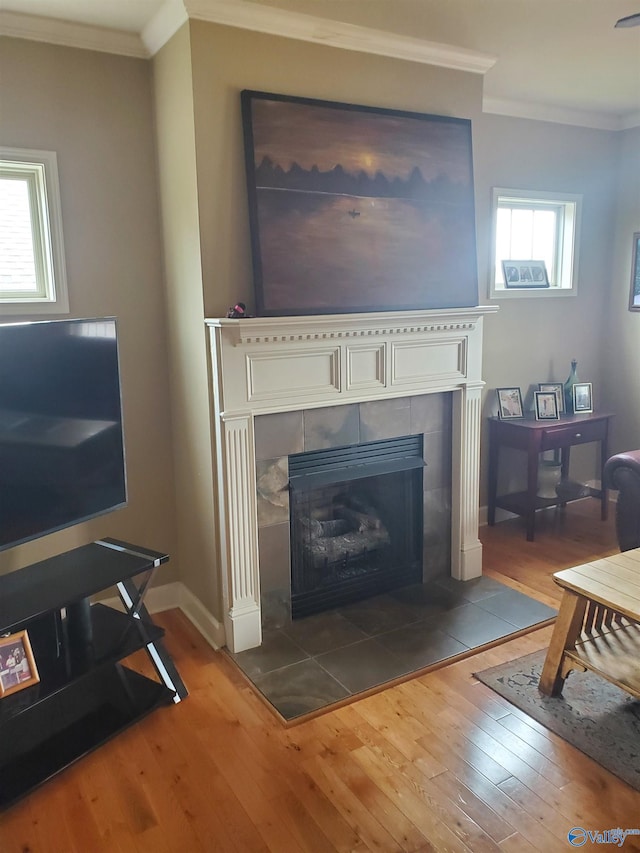 living room with wood-type flooring, crown molding, and a tile fireplace