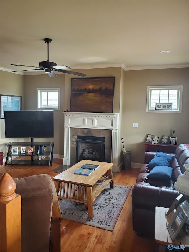 living room with a tile fireplace, wood-type flooring, and ornamental molding