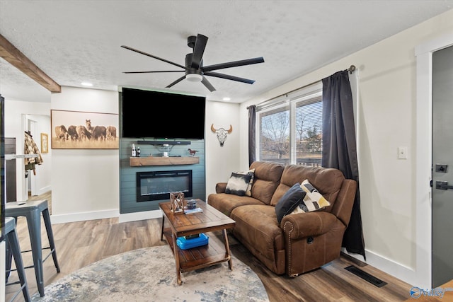 living area with a textured ceiling, a fireplace, wood finished floors, and visible vents