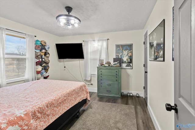 bedroom with dark wood-type flooring, a textured ceiling, and baseboards