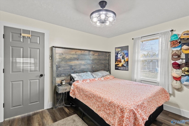 bedroom with dark wood-style flooring, a textured ceiling, and baseboards