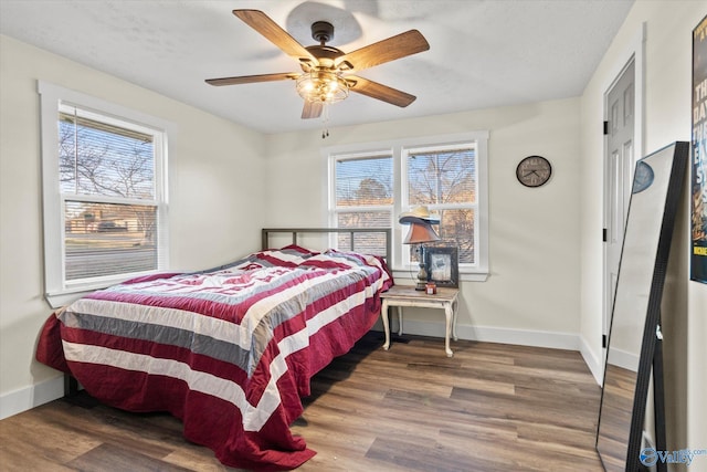 bedroom with multiple windows, baseboards, and wood finished floors