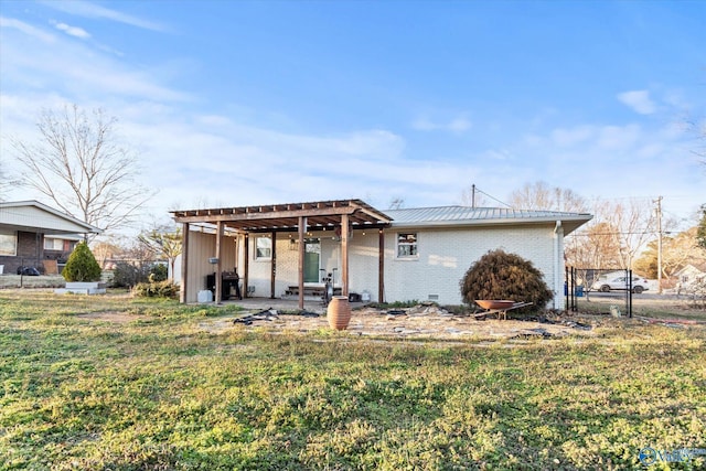 view of front of home featuring metal roof, brick siding, a front lawn, and a patio area