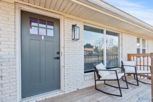 property entrance with a porch and brick siding