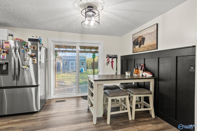 dining room with a textured ceiling, visible vents, and wood finished floors