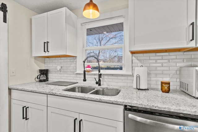 kitchen with decorative backsplash, white cabinetry, dishwasher, and a sink