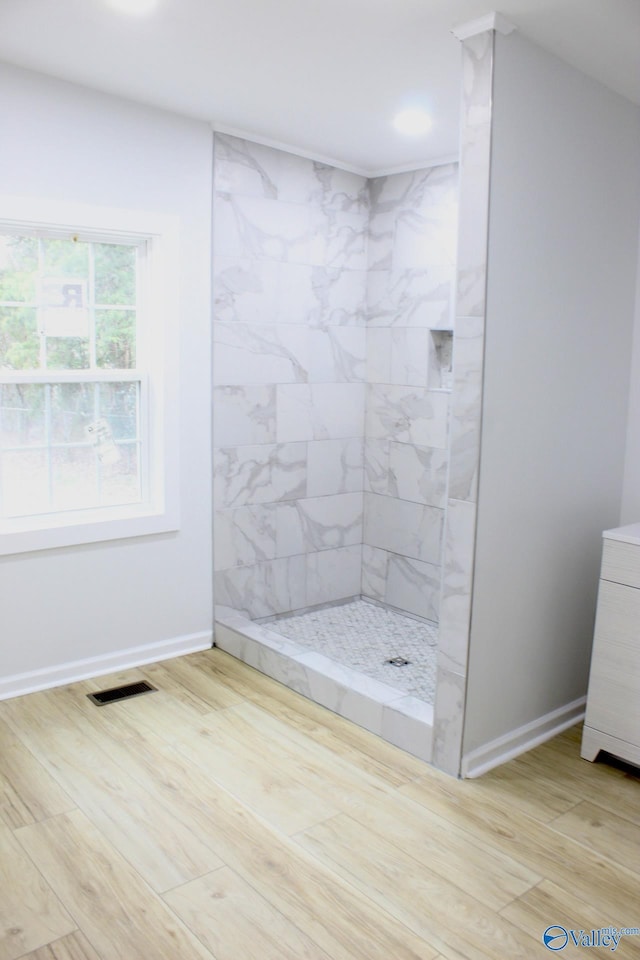 bathroom with tiled shower and wood-type flooring