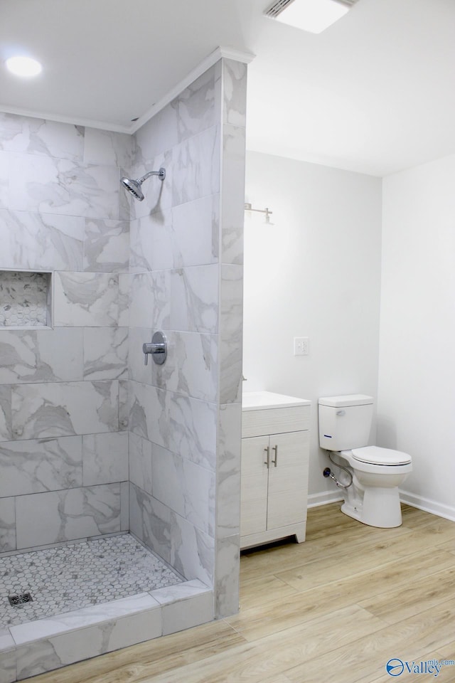 bathroom with vanity, tiled shower, hardwood / wood-style floors, and toilet