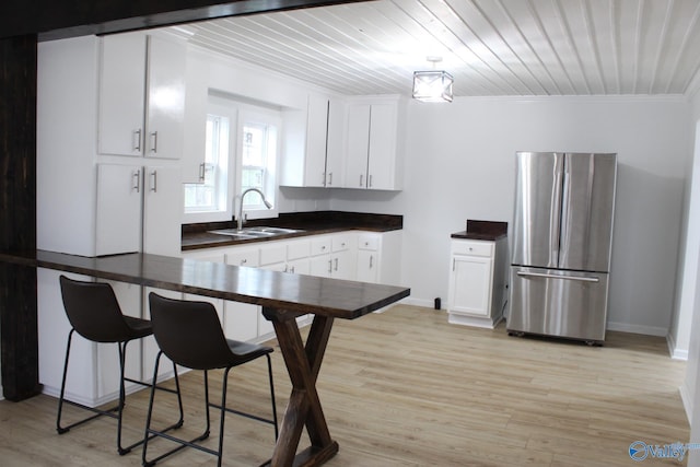 kitchen featuring stainless steel refrigerator, white cabinetry, sink, light hardwood / wood-style floors, and crown molding