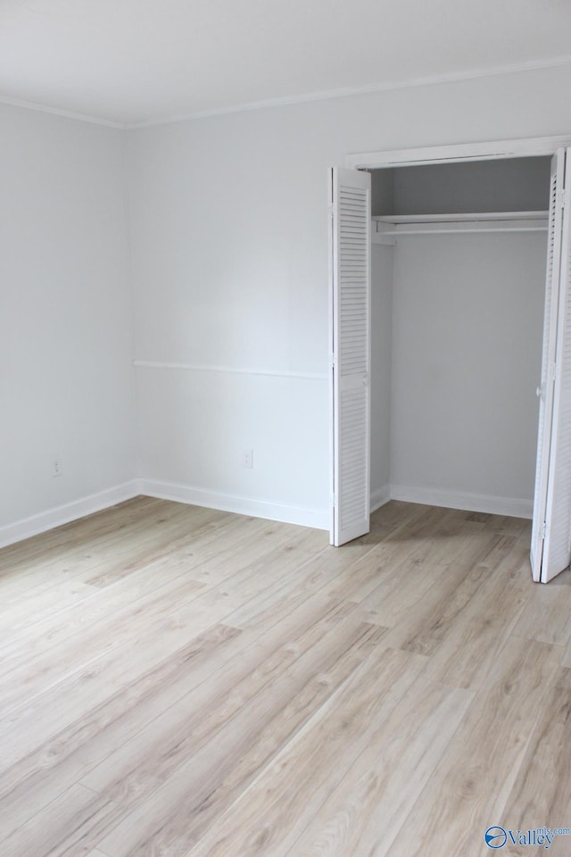 unfurnished bedroom featuring ornamental molding, light hardwood / wood-style floors, and a closet