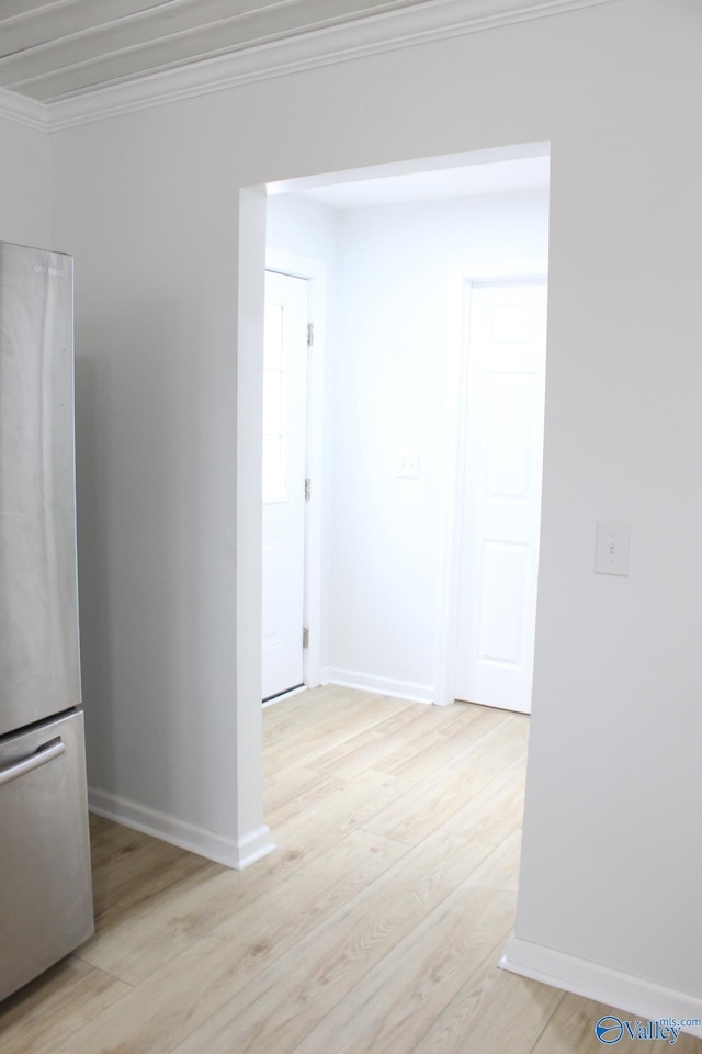 spare room featuring crown molding and light hardwood / wood-style flooring