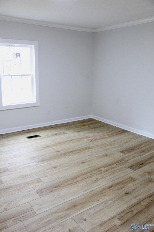 spare room featuring crown molding and light hardwood / wood-style floors