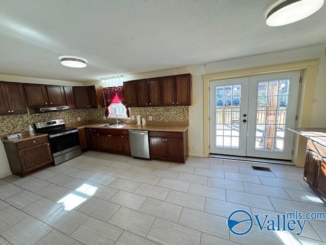 kitchen with french doors, tasteful backsplash, stainless steel appliances, ventilation hood, and sink