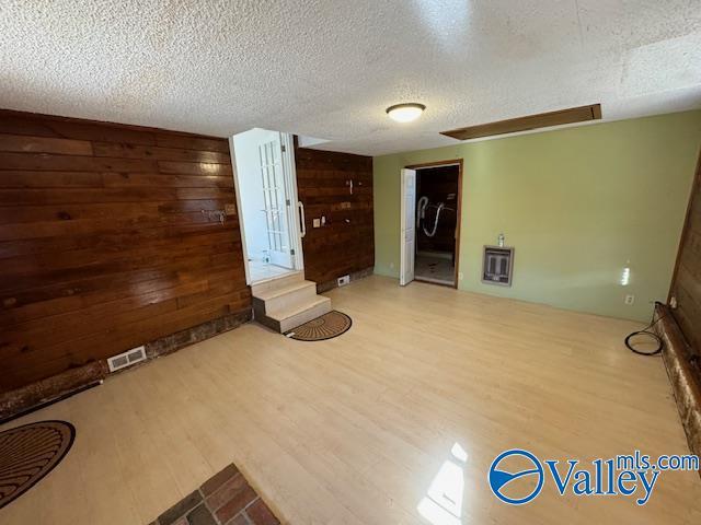 unfurnished living room with hardwood / wood-style floors, wood walls, and a textured ceiling