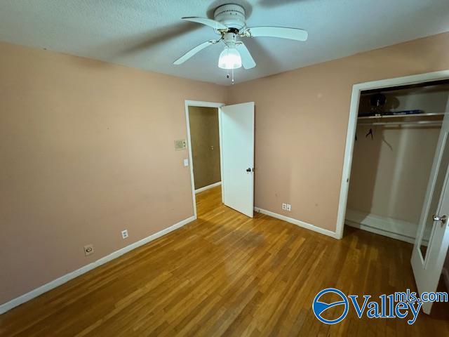 unfurnished bedroom with hardwood / wood-style floors, a closet, and ceiling fan