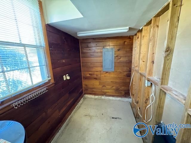 interior space with concrete floors, electric panel, and wood walls