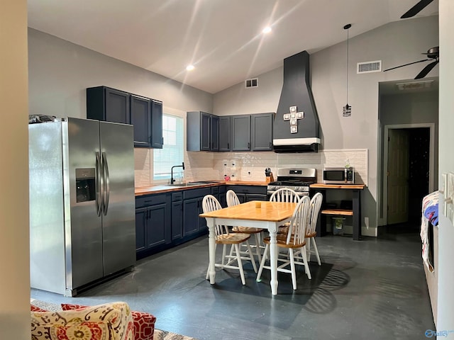 kitchen with appliances with stainless steel finishes, wall chimney exhaust hood, vaulted ceiling, and tasteful backsplash