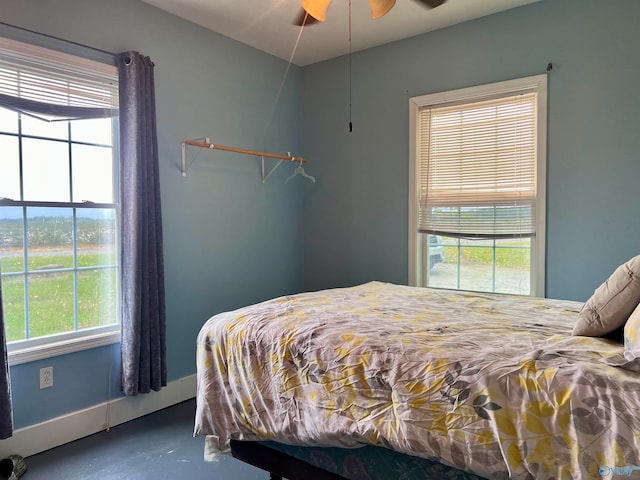 bedroom with concrete floors, ceiling fan, and multiple windows