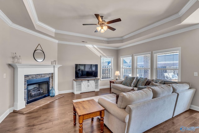 living room featuring hardwood / wood-style floors, a fireplace, ceiling fan, a raised ceiling, and crown molding