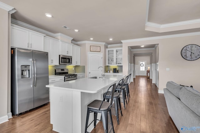 kitchen featuring sink, a breakfast bar area, stainless steel appliances, white cabinets, and light wood-type flooring