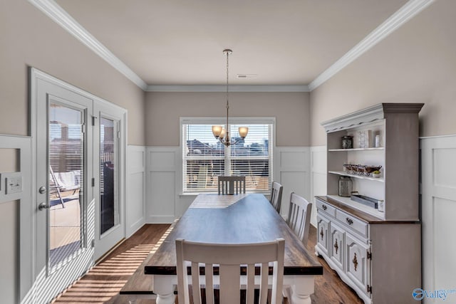 dining space with dark hardwood / wood-style flooring, ornamental molding, and a chandelier